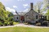 View of front facade featuring a chimney, stone siding, a standing seam roof, and metal roof