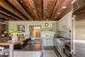 Kitchen featuring stainless steel appliances, wood ceiling with exposed beams, a sink, dark countertops, and a center island