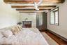 Bedroom with an AC wall unit, a baseboard heating unit, beam ceiling, dark wood-style floors, and ceiling fan