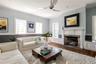 Living room featuring wood-type flooring, ceiling fan, ornamental molding, and a premium fireplace