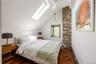 Bedroom featuring hardwood / wood-style flooring, a skylight, and vaulted ceiling