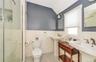 Bathroom featuring vaulted ceiling, sink, tiled shower, tile walls, and toilet