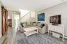 Living room featuring wood-type flooring, a barn door, baseboard heating, and crown molding