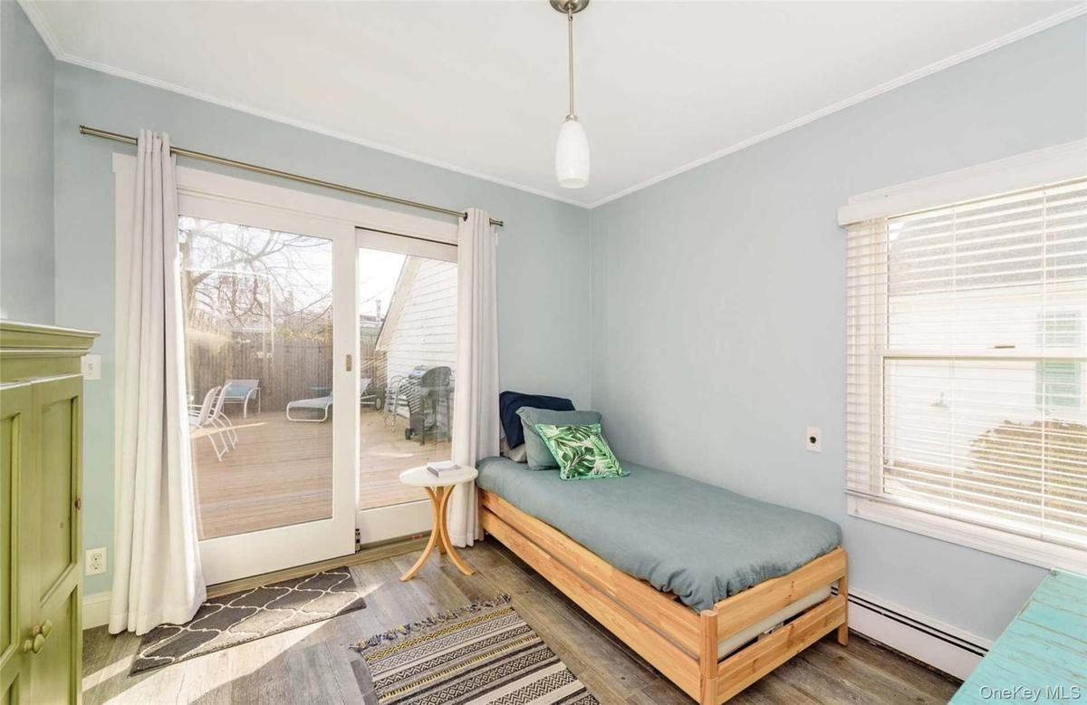 Bedroom with dark hardwood / wood-style floors, ornamental molding, access to outside, and a baseboard heating unit