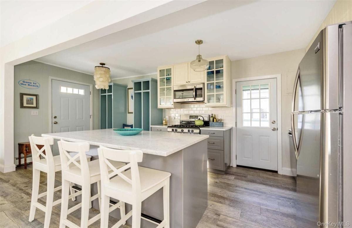Kitchen featuring pendant lighting, a center island, light stone countertops, appliances with stainless steel finishes, and wood-type flooring