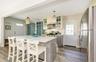 Kitchen featuring pendant lighting, a center island, light stone countertops, appliances with stainless steel finishes, and wood-type flooring