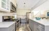 Kitchen with gray cabinetry, pendant lighting, sink, wood-type flooring, and stainless steel appliances