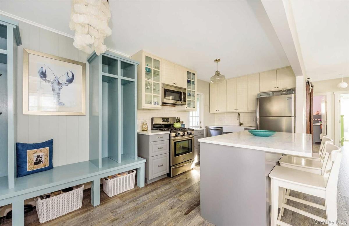 Kitchen with appliances with stainless steel finishes, tasteful backsplash, light hardwood / wood-style flooring, a center island, and hanging light f