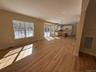 Unfurnished living room featuring light wood-style floors and hanging lights