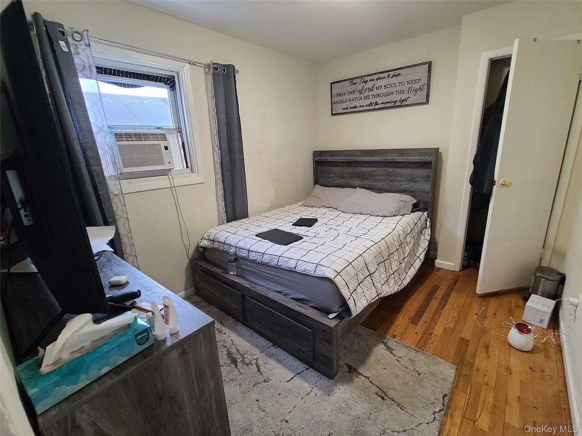 Bedroom with cooling unit, baseboards, and wood finished floors
