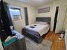 Bedroom with cooling unit, baseboards, and wood finished floors
