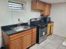 Kitchen featuring stainless steel gas stove, a sink, dark countertops, black microwave, and light tile patterned floors