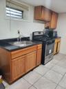 Kitchen featuring dark countertops, black microwave, gas range, light tile patterned floors, and a sink