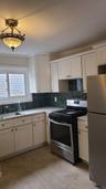 Kitchen featuring a sink, tasteful backsplash, white cabinetry, stainless steel appliances, and light countertops