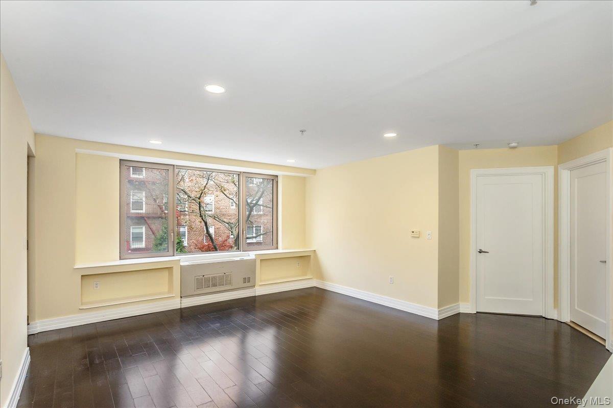 Empty room with dark wood-style flooring and recessed lighting