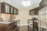 Kitchen featuring stainless steel appliances, glass insert cabinets, dark wood finished floors, and dark brown cabinets