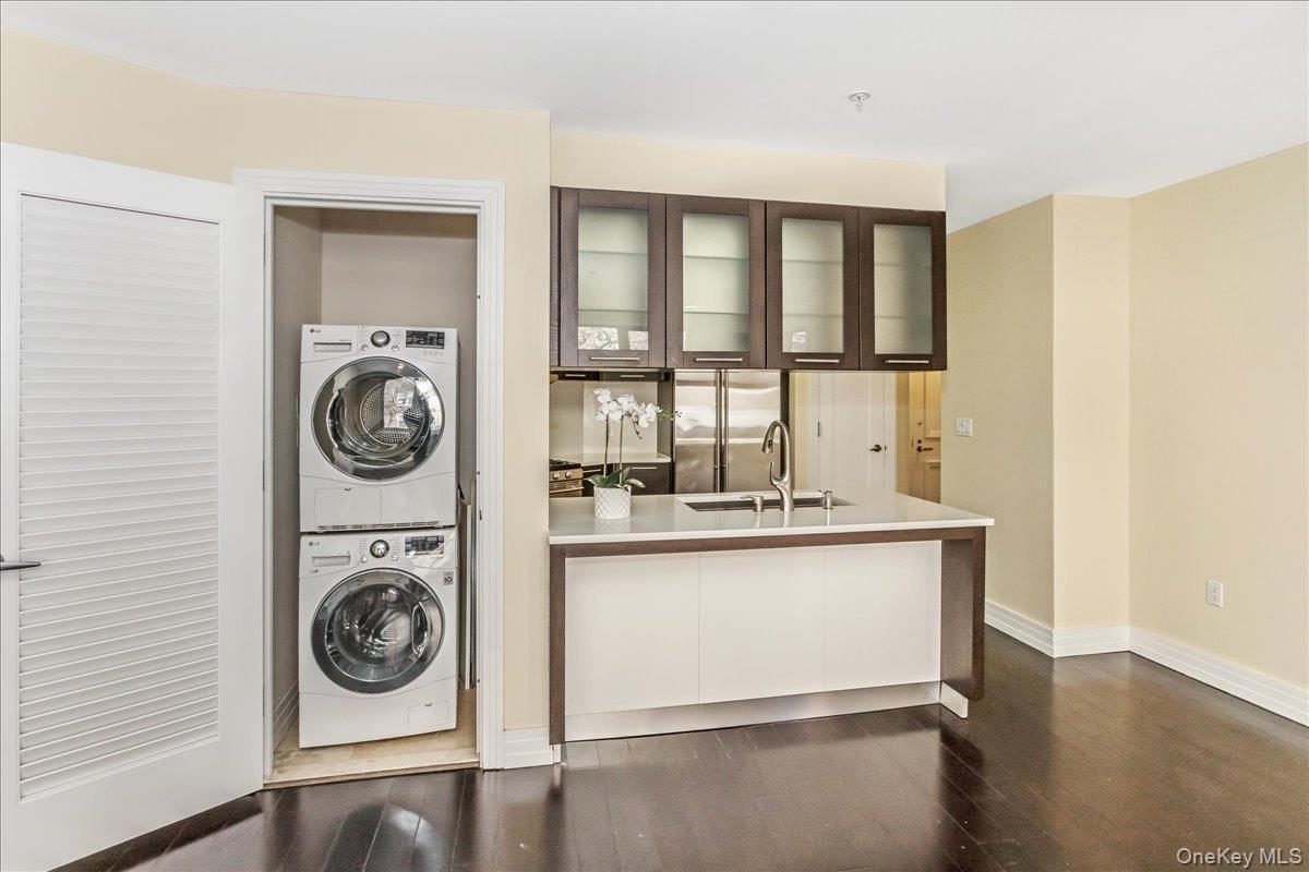 Laundry area featuring dark wood-style flooring and stacked washer and clothes dryer