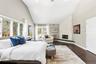 Bedroom with dark wood-style floors, a stone fireplace, lofted ceiling, and sliders to exterior.