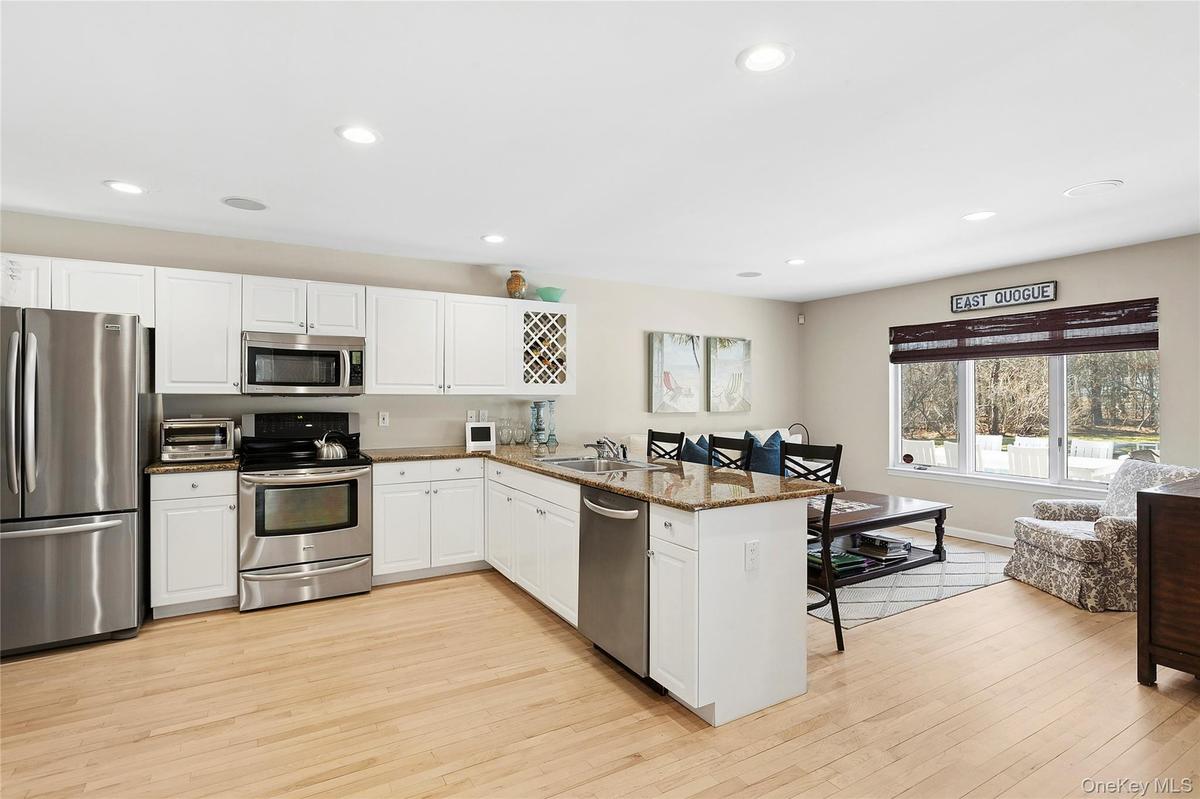 Kitchen with a kitchen breakfast bar, stainless steel appliances, white cabinets, dark stone countertops, and a peninsula