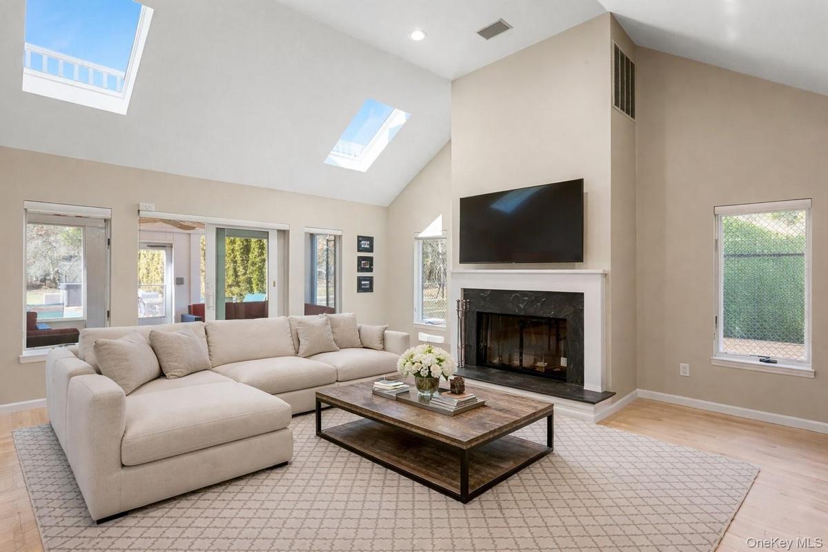 Den with skylights, valted ceiling, fireplace, and sliders to sun room.  virtually staged