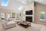 Den with skylights, valted ceiling, fireplace, and sliders to sun room.  virtually staged