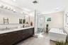 Bathroom with double vanity, a stall shower, a freestanding tub, recessed lighting, and light tile patterned floors