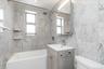 Bathroom featuring vanity, shower / bathtub combination, tile walls, and plenty of natural light