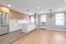 Kitchen featuring freestanding refrigerator, light wood-style floors, radiator, backsplash, pendant lighting, recessed lighting, cooling unit.