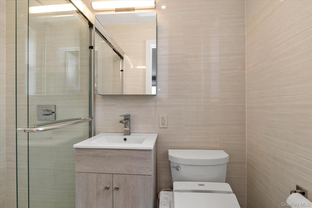 Bathroom with tile walls, vanity, and a shower stall