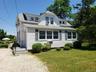 View of front of house with a shingled roof, a front yard, and a chimney