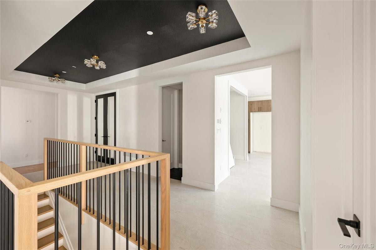 Corridor featuring a raised ceiling and an upstairs landing