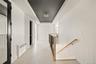 Corridor with an upstairs landing, radiator heating unit, a raised ceiling, and a chandelier