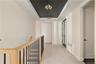 Hallway with a raised ceiling, a chandelier, and radiator