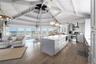 Kitchen featuring stainless steel appliances, open floor plan, dark wood-style floors, wall chimney range hood, and gray cabinets