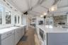 Kitchen featuring a sink, vaulted ceiling with beams, gray cabinetry, light wood-style flooring, and stainless steel appliances