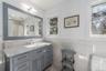 Bathroom featuring tile walls, visible vents, toilet, vanity, and wainscoting