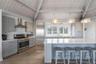 Kitchen featuring wood finished floors, stainless steel appliances, a sink, wall chimney range hood, and gray cabinets