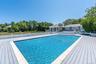 View of swimming pool with a patio area, a deck, and view of scattered trees. gunite pool