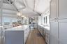 Kitchen featuring a sink, wood finished floors, a center island, stainless steel appliances, and wall chimney range hood