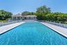 View of swimming pool with a patio and view of scattered trees. gunite pool