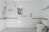 Bathroom with tile walls, a wainscoted wall, toilet, and tiled shower