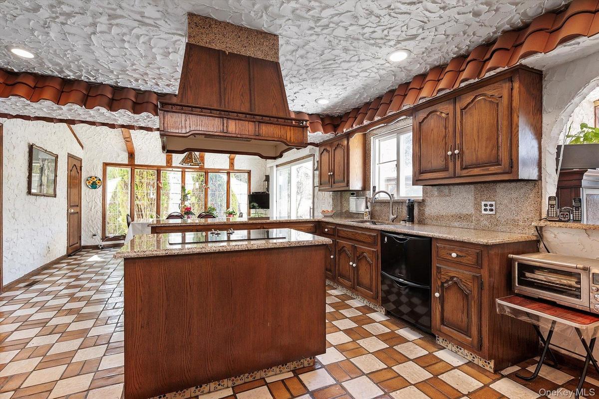 Kitchen featuring black appliances, a sink, light stone counters, and a center island