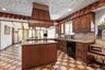 Kitchen featuring black appliances, a sink, light stone counters, and a center island