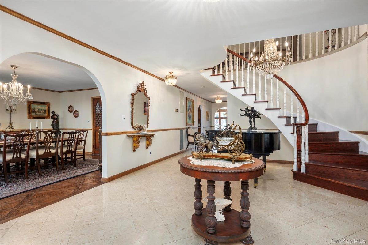 Entrance foyer featuring a chandelier, stairway, baseboards, and crown molding