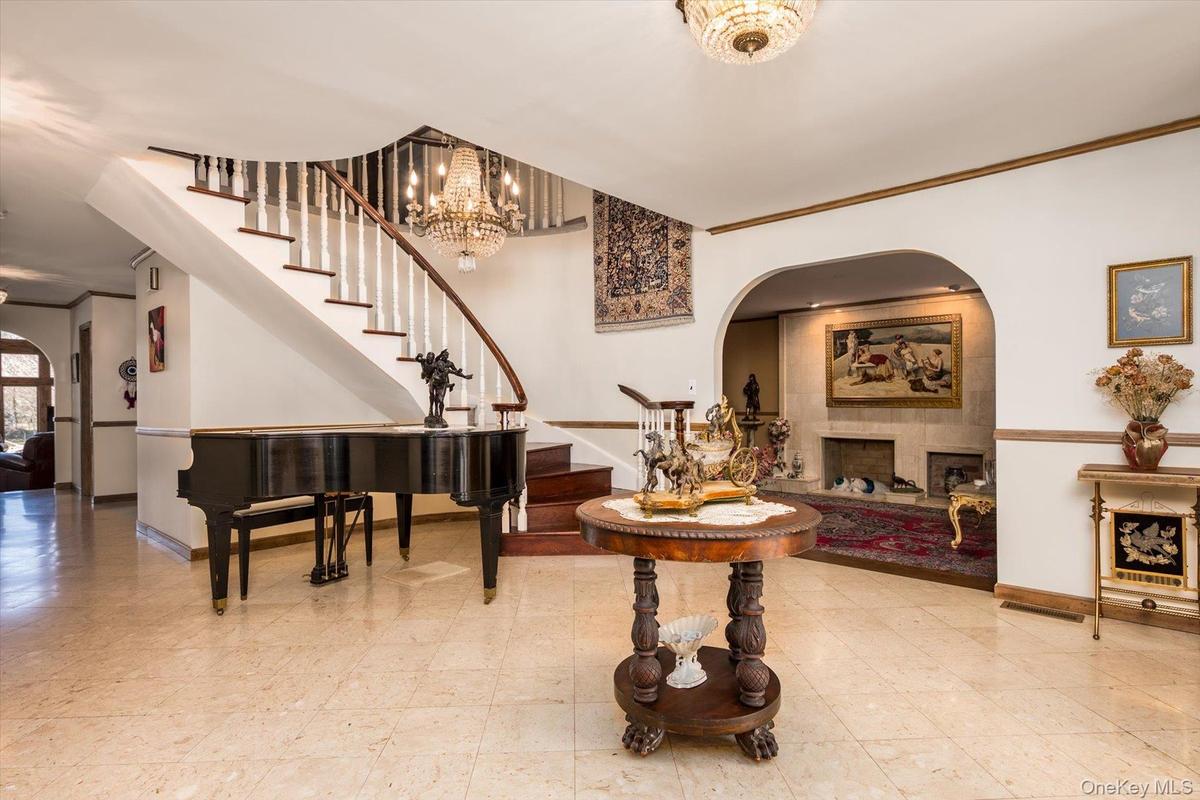 Foyer with arched walkways, stairway, baseboards, a fireplace, and ornamental molding