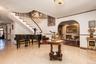 Foyer with arched walkways, stairway, baseboards, a fireplace, and ornamental molding