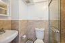 Full second bath featuring a shower stall, a wainscoted wall, and tile walls