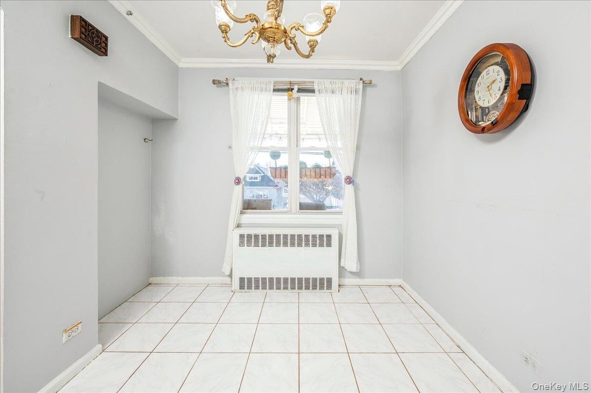 Dining area featuring radiator heating unit, a chandelier, and crown molding