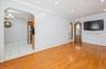 Living room with arched walkways, crown molding, light wood-style floors, and a chandelier