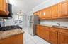 Kitchen featuring wood finish cabinets, light granite countertops, crown molding, stainless steel appliances, and decorative backsplash